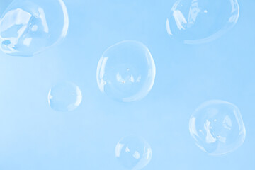 Transparent drops of acid on a blue background, top view. Liquid cosmetic product on a colored surface.