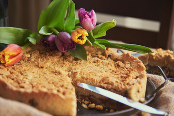 Homemade cake and a piece cut from it on vintage plates next to a bouquet of tulips.