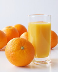 A glass of freshly squeezed orange juice and a large number of oranges lie on the table so that every morning is decorated with a bright orange color, saturated with vitamins and energy, it is joyful
