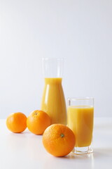 Fototapeta na wymiar The morning should start right - there is a glass of freshly squeezed orange juice on the table, a little further - a jug of juice and oranges on the table - a boost of energy and vytamin C for the wh