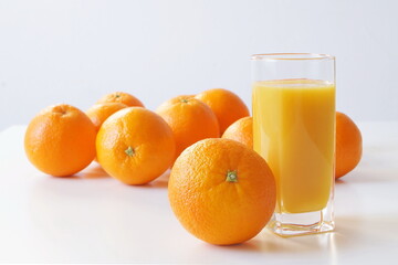 Oranges are on the table, also on the table is a glass of freshly squeezed juice for breakfast, a good start to the day and enriching the body with vitamin C