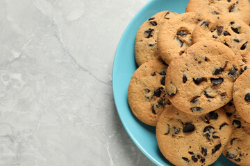 Plate with delicious chocolate chip cookies on grey marble table, top view. Space for text