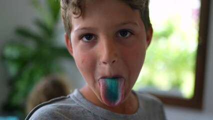 Young boy sticking blue tongue looking out camera child sticks colorful tongue