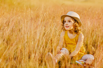 A happy child is sitting in the grass of a outumn meadow