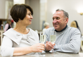Mature man and woman drinking champagne in theater lobby