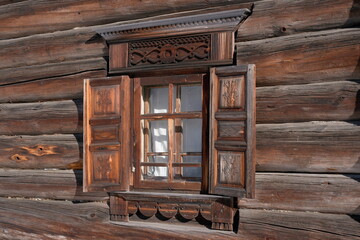 window with open, carved shutters in a wooden house