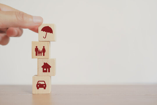 senior's hand arrange stack of wooden cube block with umbrella on top, insurance concept for health, life ,property, travel