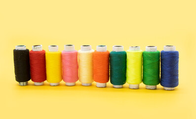 different color yarn or spool thread like rainbow over on yellow background,red,yellow,blue,black color yarn