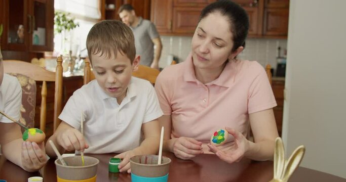 Mom helps her sons paint Easter eggs. Easter atmosphere