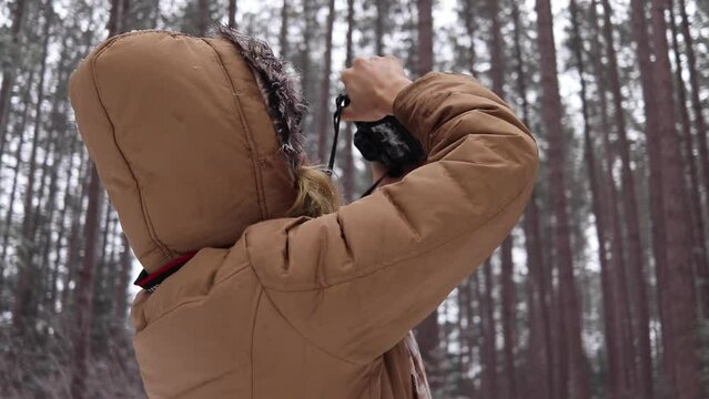Medium shot of a young women taking photos of a pine forest in Canada.
