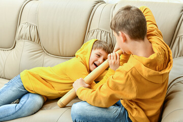 Two boys are sitting on the couch and fighting. Fight and quarrel of younger brothers.