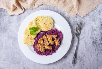 Roast pork with dumplings and sauerkraut. Typical Czech national dish with homemade bread dumplings red cabbage on stone background. Top view.