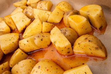 Detail of American potatoes prepared for baking in the oven. chopped fresh potatoes into small pieces and drizzled with oil and spices.