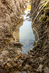 Detail of an excavation full of water for laying cable and water pipes after the rain