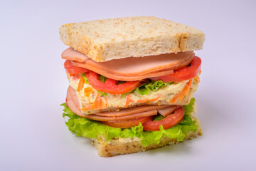 Big sandwich with smoked ham, cream, lettuce and tomato isolated on white background. Fast food.