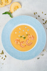 Delicious yellow pumpkin cream soup with shrimp