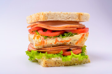 Big sandwich with smoked ham, cream, lettuce and tomato isolated on white background. Fast food.