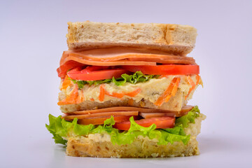 Big sandwich with smoked ham, cream, lettuce and tomato isolated on white background. Fast food.