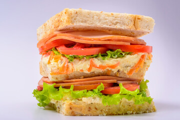 Big sandwich with smoked ham, cream, lettuce and tomato isolated on white background. Fast food.