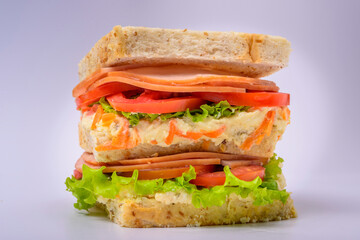 Big sandwich with smoked ham, cream, lettuce and tomato isolated on white background. Fast food.