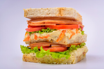 Big sandwich with smoked ham, cream, lettuce and tomato isolated on white background. Fast food.