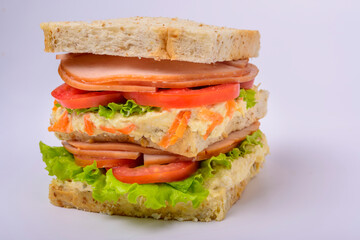 Big sandwich with smoked ham, cream, lettuce and tomato isolated on white background. Fast food.