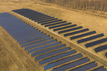 Farma paneli solarnych na równinie pokrytej suchą żółtą trawą. - 494682506