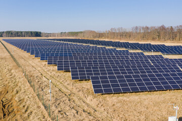 Farma paneli solarnych na równinie pokrytej suchą żółtą trawą. - 494682533