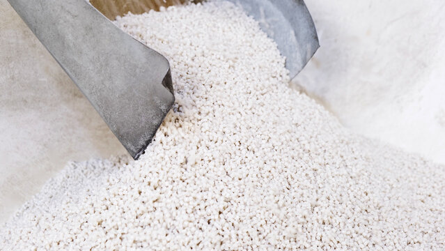 White secondary processing plastic granule comes out of the granulator crusher into small granules. Concept of plastic recycling, production of secondary raw materials. White Plastic pellets crumbles