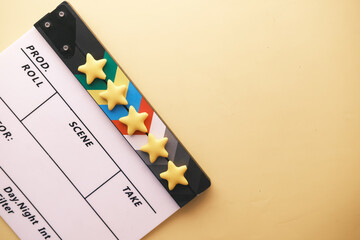 Rating golden stars and movie clapper board on color background 