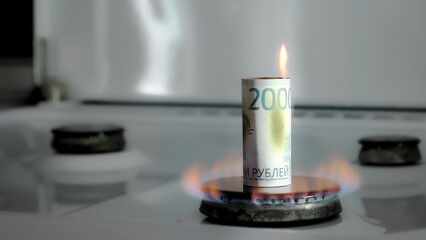 Concept of gas crisis. 2000 Russian rubles bill is burning on a kitchen stove burner. Cash money....