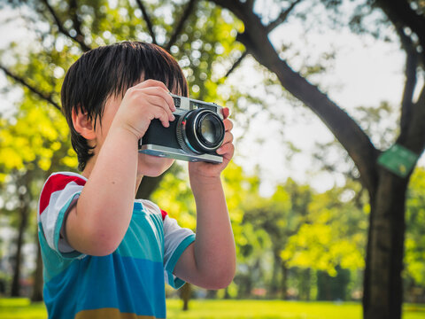 little kids boy taking a picture using a vintage retro film in nature park