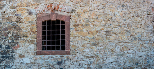 Fototapeta na wymiar Banner with ancient stone wall and a metal grid window as a prison with copy space background. Concept of freedom and liberty.