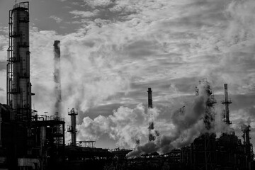 Soft backlit oil refinery in the middle of clouds and steam. Converted black and white.