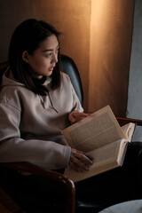 Naklejka premium Shot of young asian female student sitting at table and writing on notebook. Young female student studying in cafe.