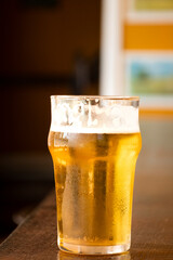 close up half pint of pale lager pilsen beer with blurred background on pub counter
