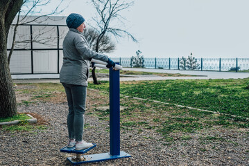 an adult woman goes in for sports on exercise equipment outdoors to maintain health. the concept of a healthy lifestyle in the older generation, maintaining youth and good spirits