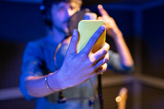 male rapper singing in recording studio with smartphone