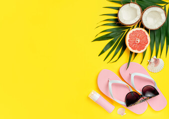 Beach accessories and sunscreen bottle on bright yellow background. Flat lay, copy space.