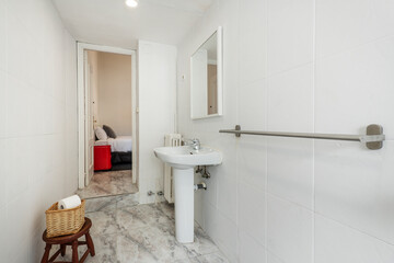 Bathroom with white porcelain sink on foot of the same material, square mirror and white tiles