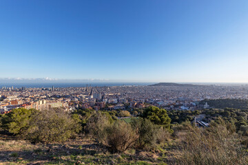 View of the city of Barcelona from the mountain on a sunny day. Urban landscape. Blue sky over the city.