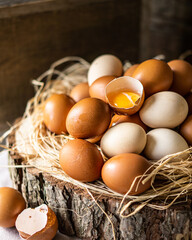 Front view of fresh raw eggs on hay and wood over wooden brown rustic background