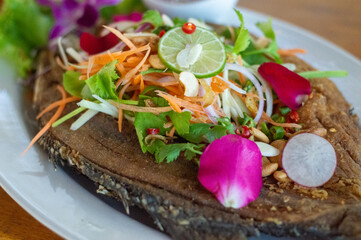 On white ceramic, a fish fry is nicely organized and decorated with onion, lemon, and tomato slices.