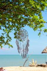 On a blue sky background, there is a dreamcatcher.