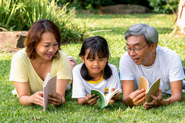 Fototapeta premium Happy family reading book relax in weekend holiday lifestyle park outdoor nature background.