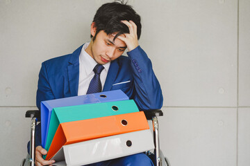 businessman with folders Sitting on a wheelchair, working hard until sick.