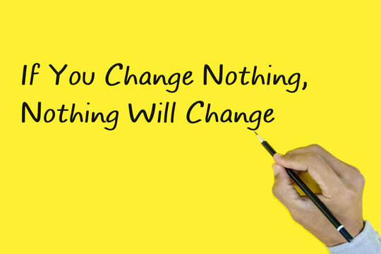 Male hand writing "If You Change Nothing, Nothing Will Change" on yellow background.