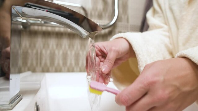 Women's hands in the bathroom washes a splint from bruxism. Preventive regular cleaning of the aligner to correct the bite and align the teeth