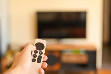 Hand with tv remote control switching television on at home. smart tv. selective focus