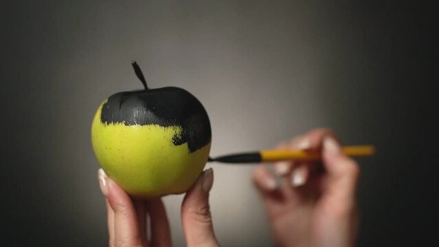 girl paints a green apple matte black